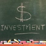 $ investment written on a green chalk board