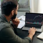 Smart broker investor, uses a laptop to analyze the financial market of cryptocurrencies, invests in