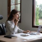 Woman accountant using calculator and computer in office, finance and accounting concept.